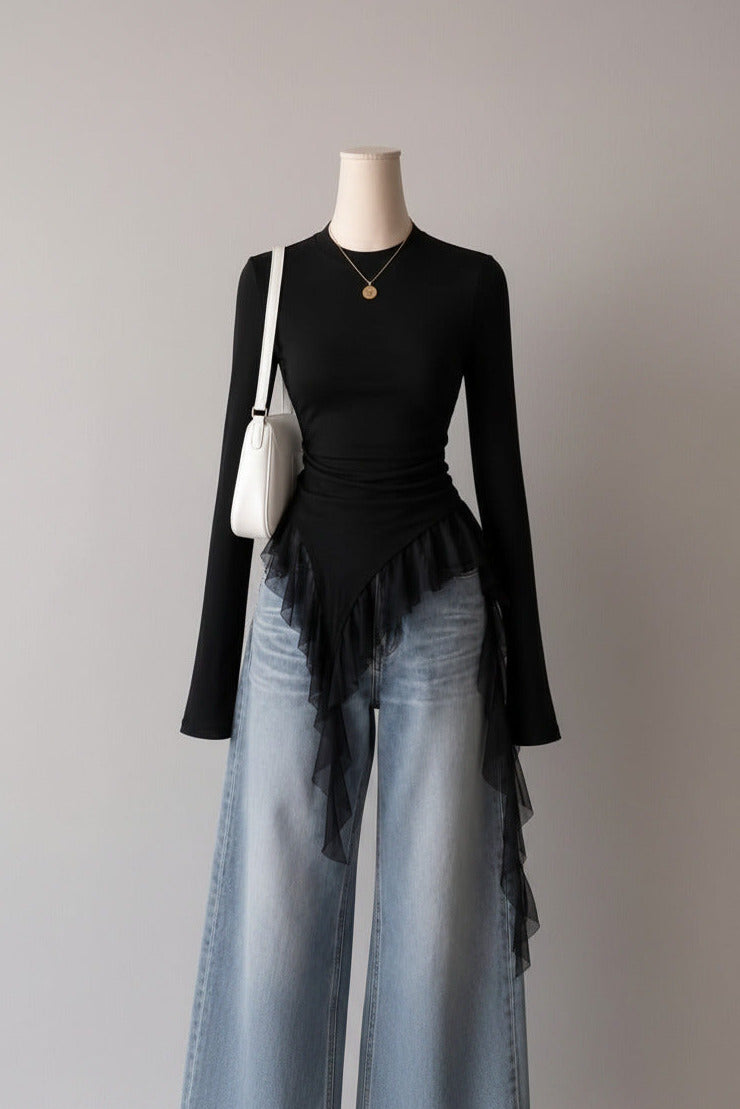 Mannequin wearing a black top and light blue jeans with a white bag, against a wall with framed pictures.